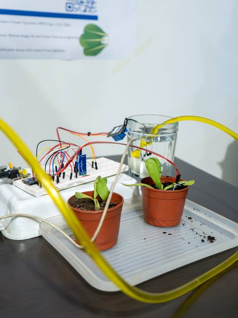 Una representación de un sistema de riego automatizado para plantas que incluye dos macetas y sensores en una mesa.