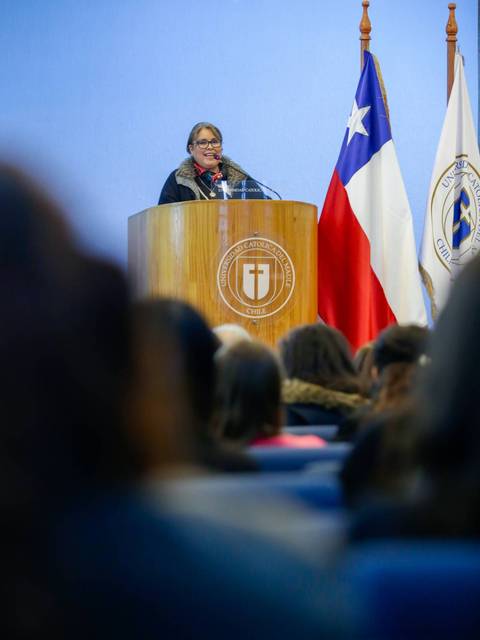 Una mujer habla en un podio frente a una audiencia en un evento formal.