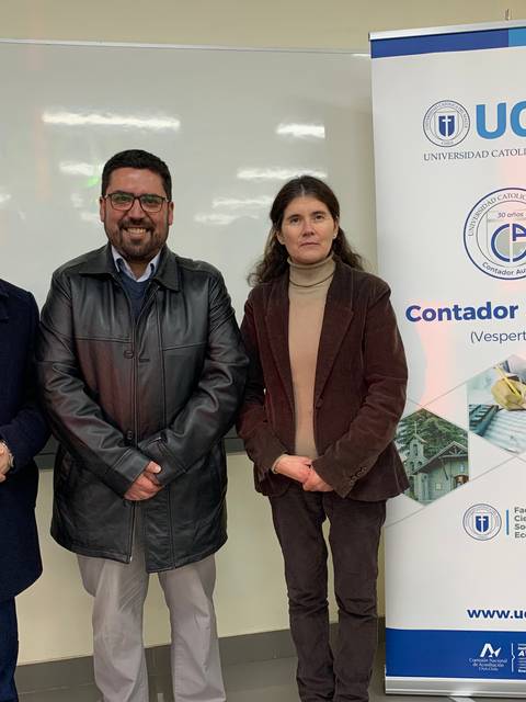 Tres personas posan frente a un banner de la Universidad Católica del Maule.