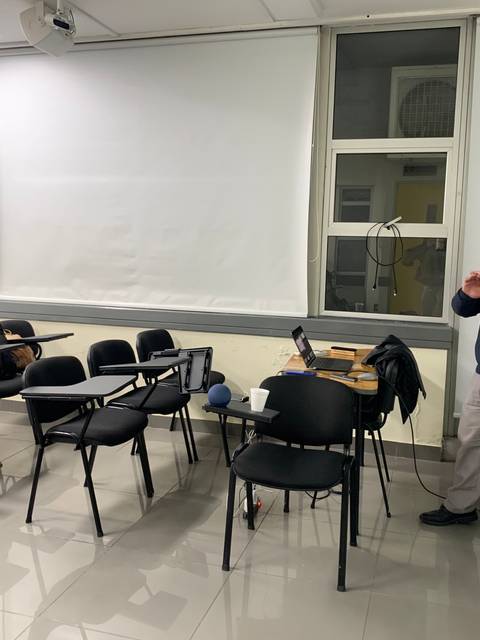 Un hombre está dando una presentación frente a un grupo de personas sentadas en un aula.