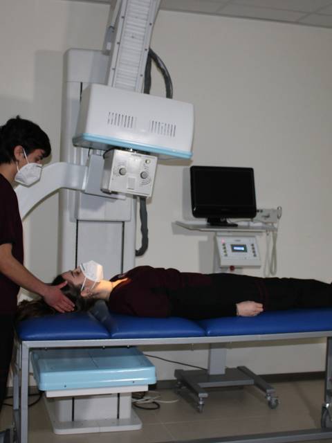 Un técnico de radiología está preparando a un paciente en una sala de exploración radiológica.