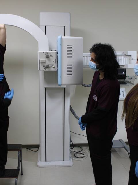Un grupo de estudiantes observa el proceso de un examen de radiología en un entorno clínico.