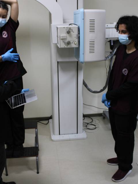 Un grupo de estudiantes de medicina se encuentra en una sala de radiología, observando un procedimiento.