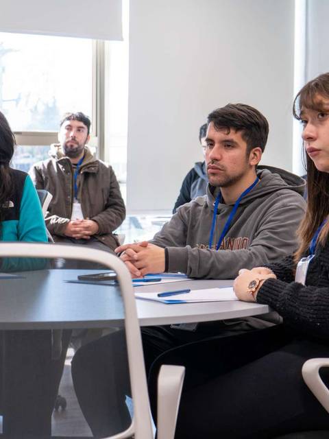 Un grupo de personas escuchando atentamente en un aula moderna.