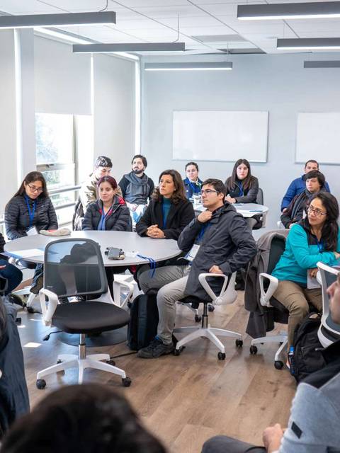 Un orador presenta ante un grupo de personas en un aula moderna.