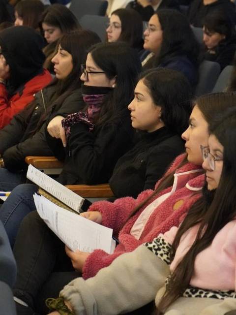 Un grupo de jóvenes mujeres escuchando atentamente en un auditorio.