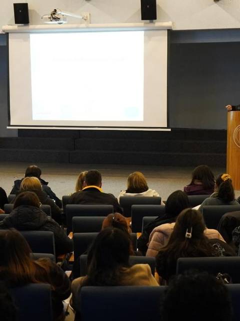 Un conferencista habla frente a una audiencia en un auditorio universitario.