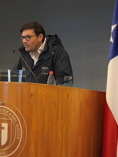Una persona está en un podio de madera hablando en una conferencia en la Universidad Católica de Valparaíso, Chile.