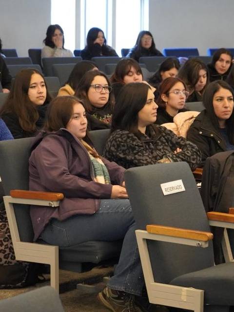 Un grupo de estudiantes sentados en una sala en un evento o conferencia.