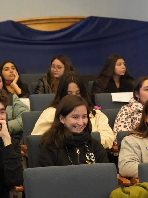 Un grupo de estudiantes en una sala, sentados y atentos durante una presentación.