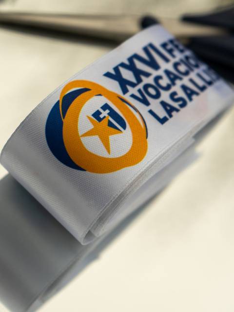 Una cinta con el texto de un evento sobre educación en un plato plateado junto a unas tijeras.