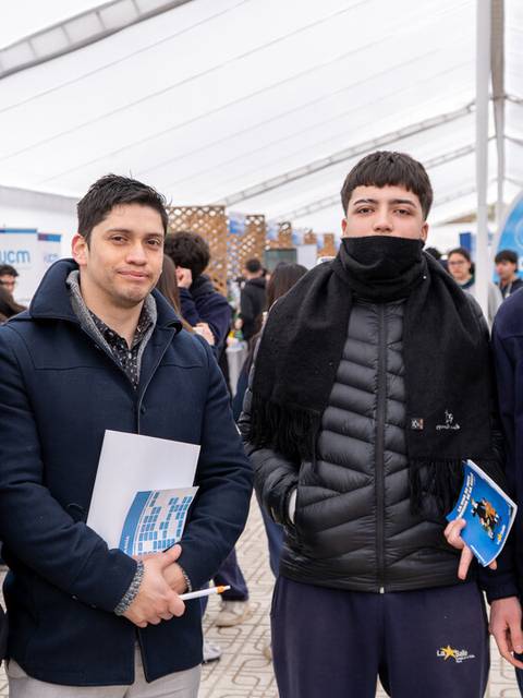 Cuatro jóvenes posan en un evento al aire libre bajo una carpa.