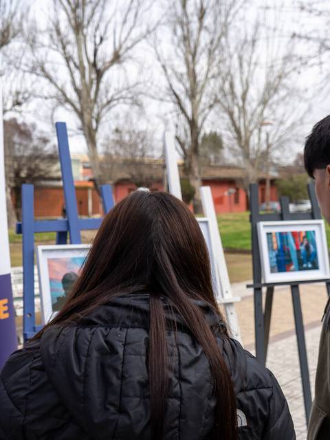 Un grupo de personas observa una exposición de fotografías al aire libre.