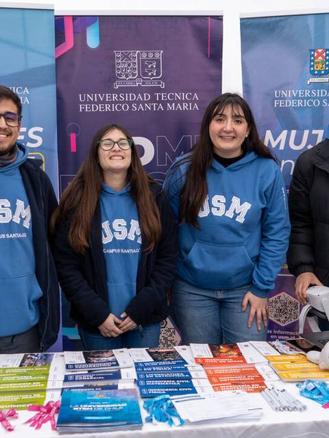 Cuatro personas posan en un stand de la Universidad Técnica Federico Santa María durante un evento.