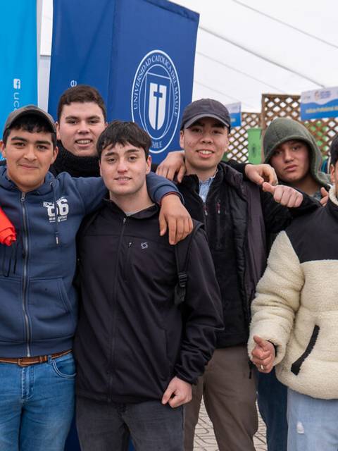 Un grupo de jóvenes sonríen y posan juntos en un evento al aire libre.
