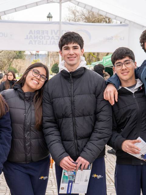 Grupo de estudiantes sonrientes posando juntos en un evento al aire libre.