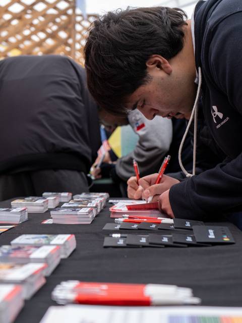 Un hombre está escribiendo en una mesa llena de objetos promocionales.