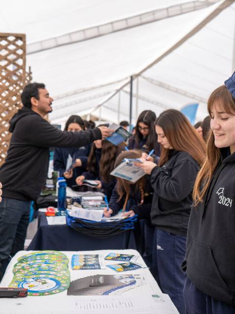 Una actividad educativa donde un carabinero interactúa con jóvenes en un stand.
