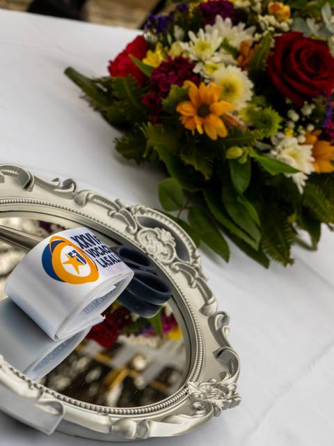 Una bandeja decorativa sostiene un objeto envuelto en papel sobre una mesa, al lado de un ramo de flores coloridas.