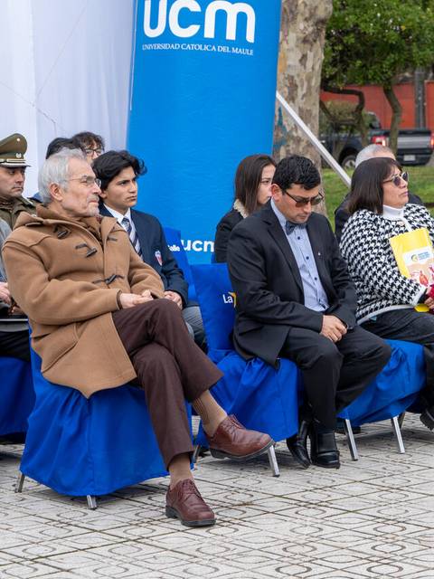 Un grupo de personas sentadas en sillas en un evento al aire libre.