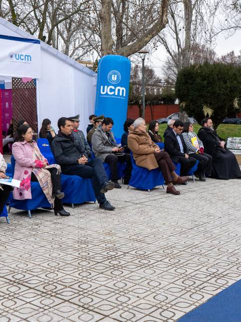 Una feria vocacional con un grupo de personas sentadas frente a un stand en un ambiente al aire libre.