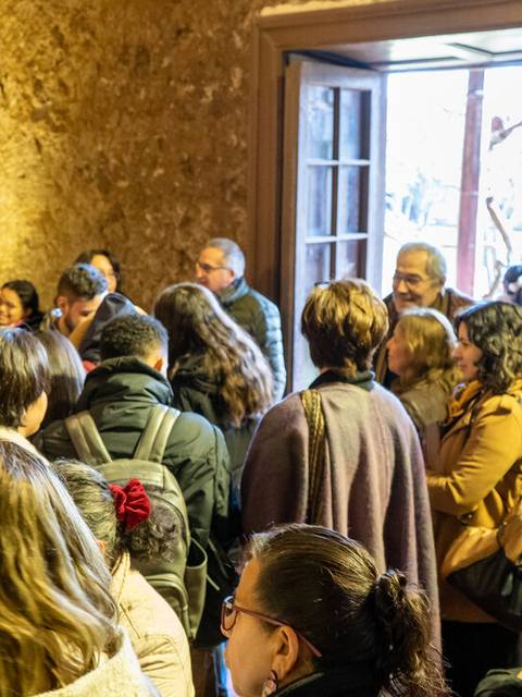 Una multitud de personas se encuentra en un espacio cerrado, esperando con atención cerca de una entrada.
