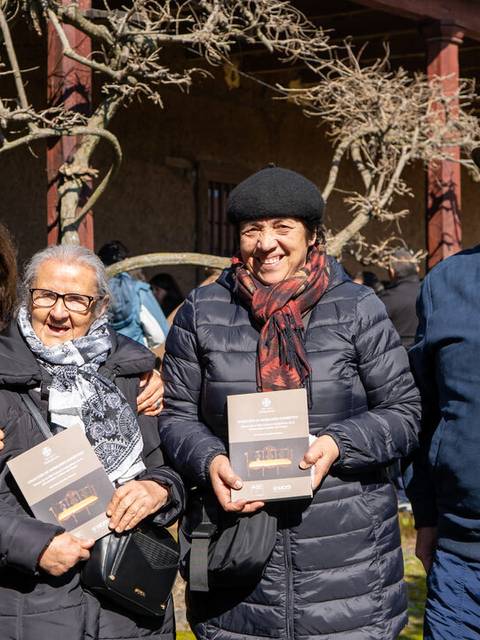 Un grupo de cuatro personas sonríe mientras sostienen libros en un entorno al aire libre.