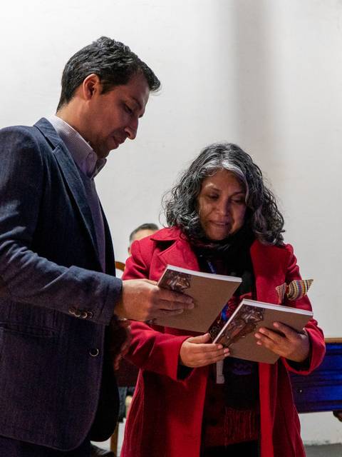 Dos personas intercambian libros durante un evento en un ambiente acogedor.