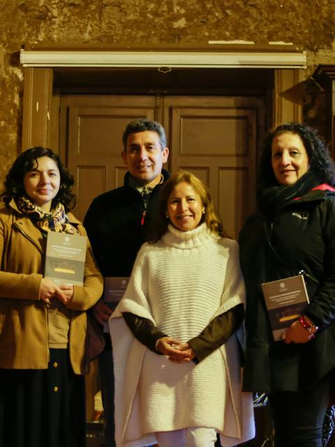 Cuatro personas posan en una entrada con paredes de color marrón.