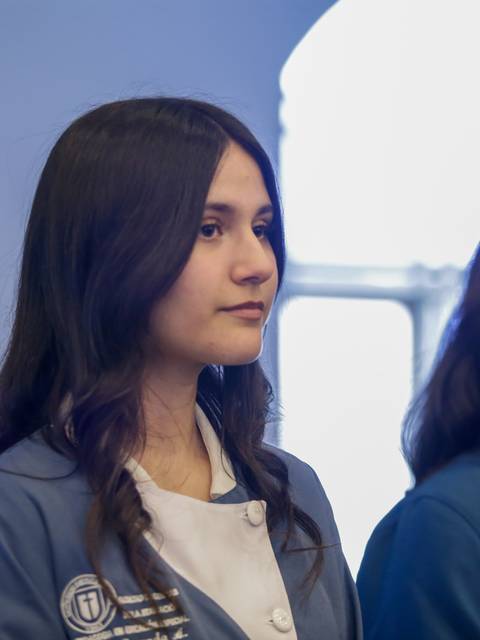 Dos jóvenes de pie, con uniformes de cocina, observando atentamente lo que sucede a su alrededor.