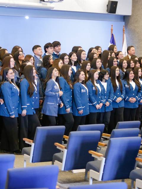 Una gran cantidad de personas posando juntas en un espacio interior con sillas azules.