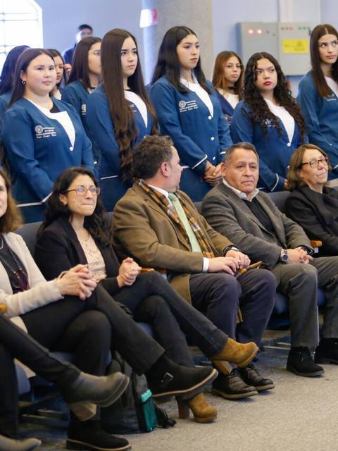 Un grupo de jóvenes y adultos sentados y de pie en un evento formal.