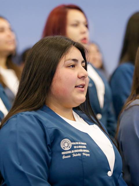 Un grupo de jóvenes mujeres cantando en un evento formal.