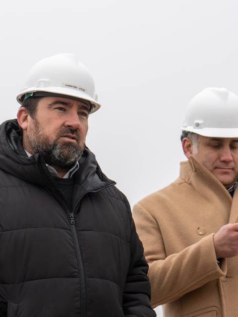 Dos hombres con cascos de seguridad observan un proyecto de construcción en un ambiente nublado.