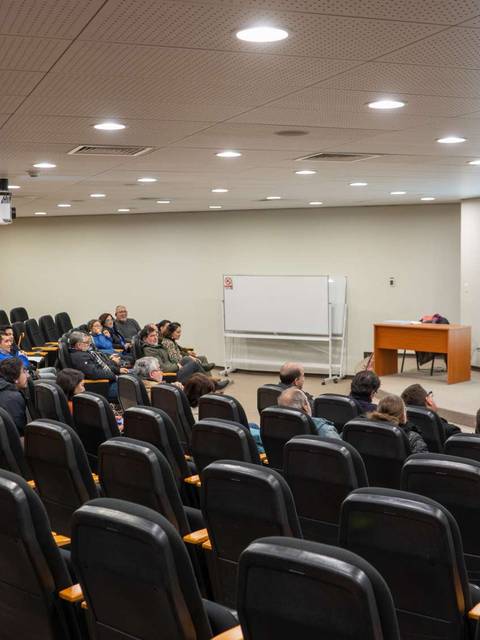Una sala de conferencias con un orador frente a un público sentado.