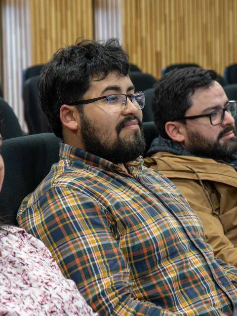 Tres personas sentadas en un auditorio durante un evento.