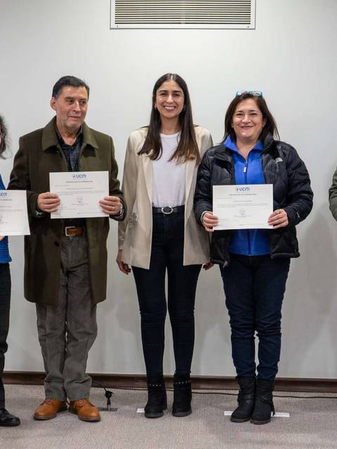 Seis personas posan en una sala con certificados en manos y una bandera de Chile al fondo.