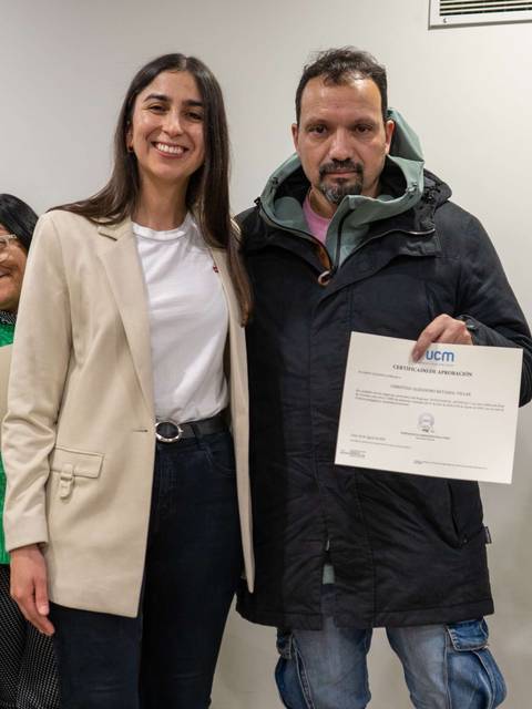 Una mujer y un hombre posan juntos sosteniendo un certificado en un evento.