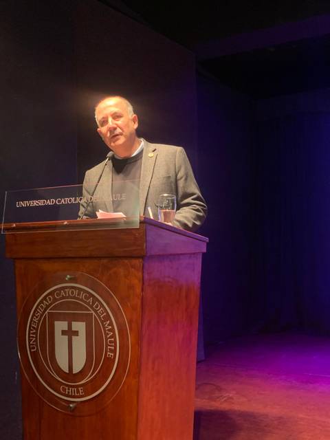 Un hombre habla desde un estrado en un evento en la Universidad Católica del Maule, Chile.