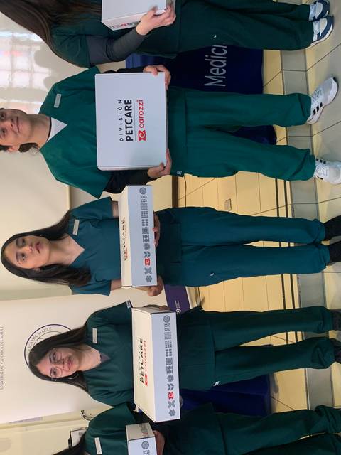 Un grupo de personas en uniformes médicos sostiene cajas en un evento.