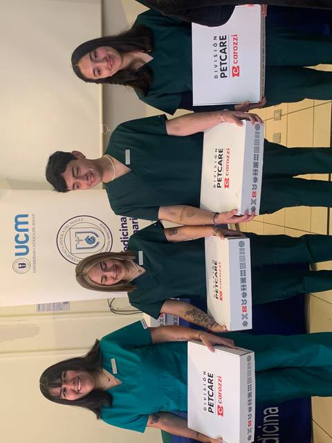 Un grupo de cuatro personas en uniformes de trabajo sostiene cajas en un entorno de oficina.