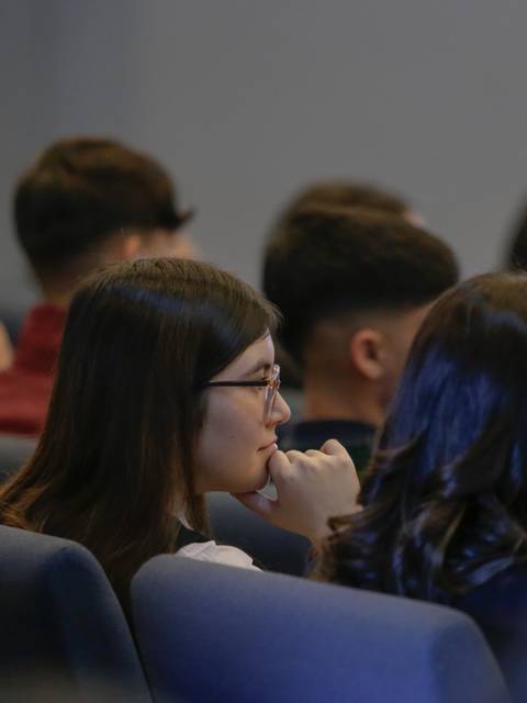 Un grupo de personas sentadas en una conferencia, concentrándose en la charla.