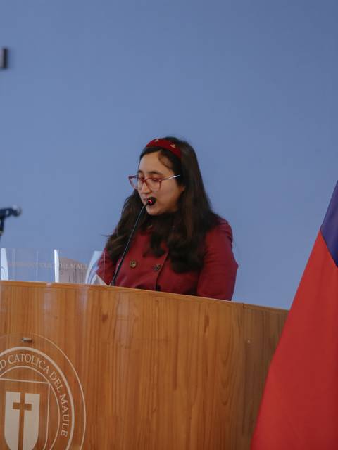 Una mujer habla desde un podio en un evento en una universidad chilena.