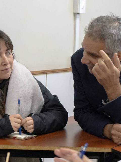 Una mujer y un hombre conversan en un entorno académico.