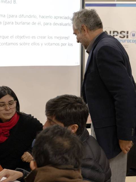 Un grupo de personas participa en una actividad en un aula donde un instructor interactúa con los asistentes.