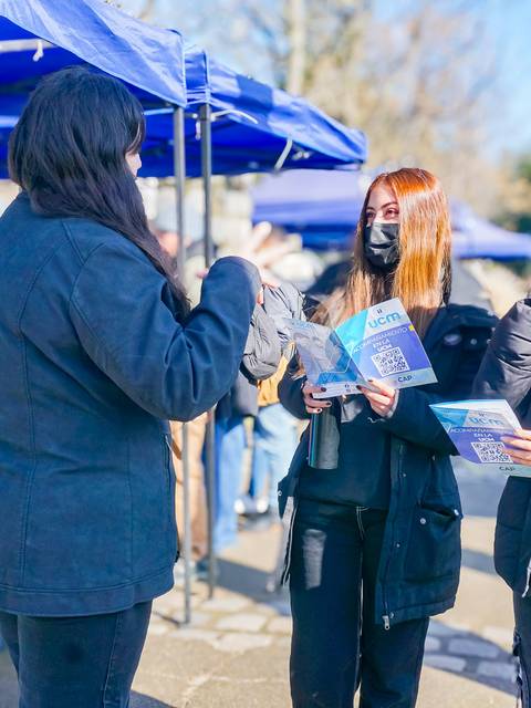 Un grupo de tres jóvenes conversando en un mercado al aire libre.