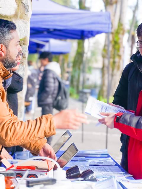 Una persona está conversando con un vendedor en un mercado al aire libre.