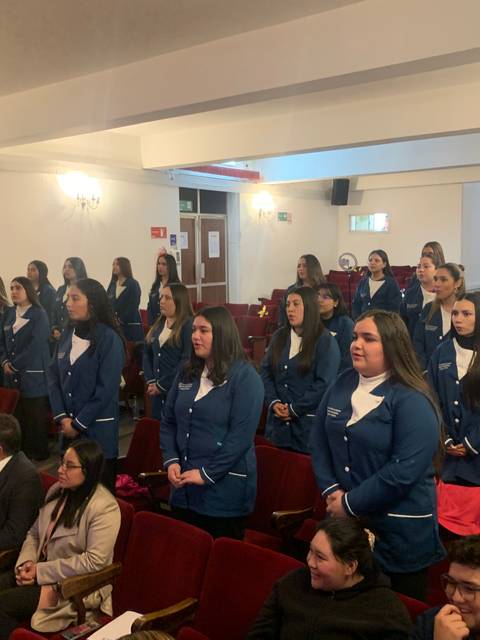 Un grupo de personas de pie en un auditorio, todas vestidas con uniformes similares.