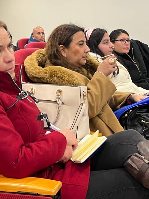 Un grupo de mujeres sentadas en un auditorio prestando atención a una presentación.