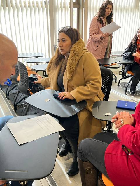 Un grupo de personas en un aula discutiendo y revisando documentos.
